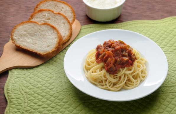 Spaghetti with Italian red sauce with onions and bell peppers and a side of bread